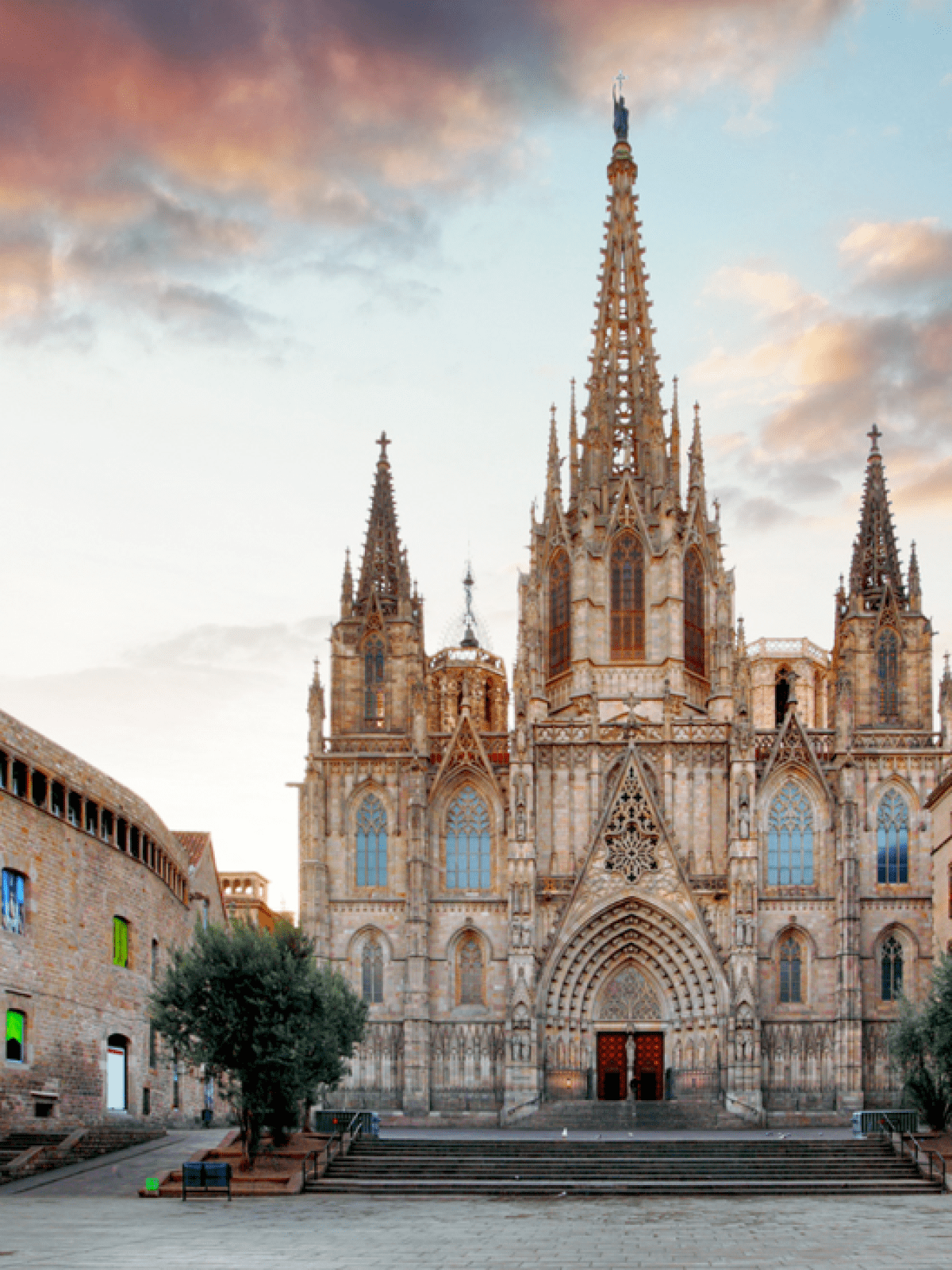 Gothic cathedral with spires at sunset, surrounded by historic buildings.