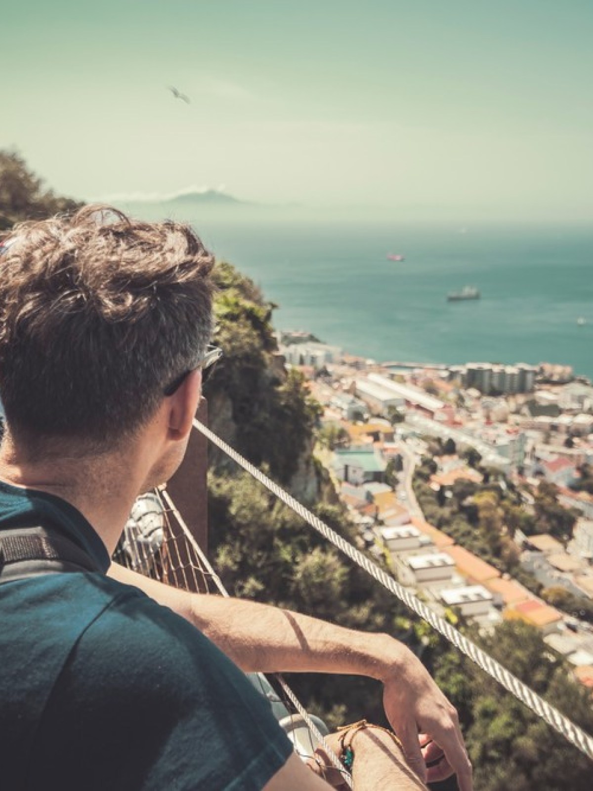 Three men on a mountain lookout, overlooking a city and ocean below.