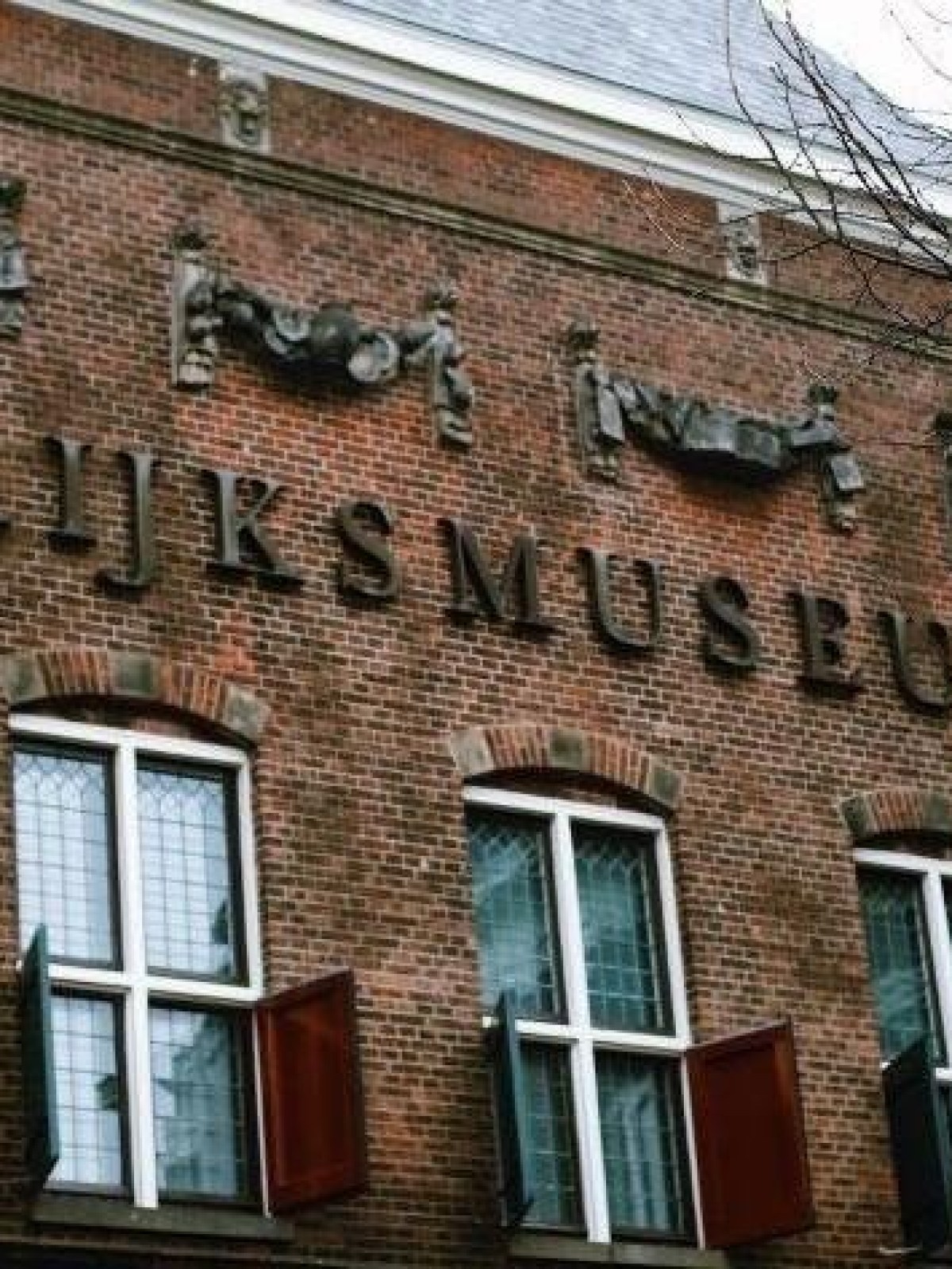 Brick facade of a building with 'Rijksmuseum' sign and decorative elements above windows.
