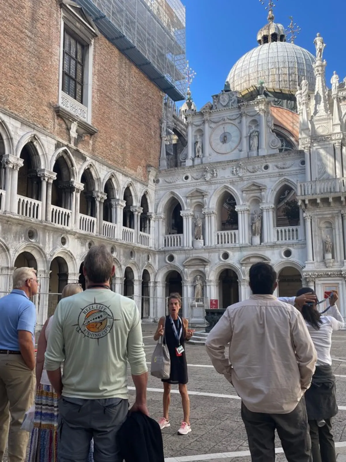Tour group in a historic courtyard with ornate architecture and sculptures.