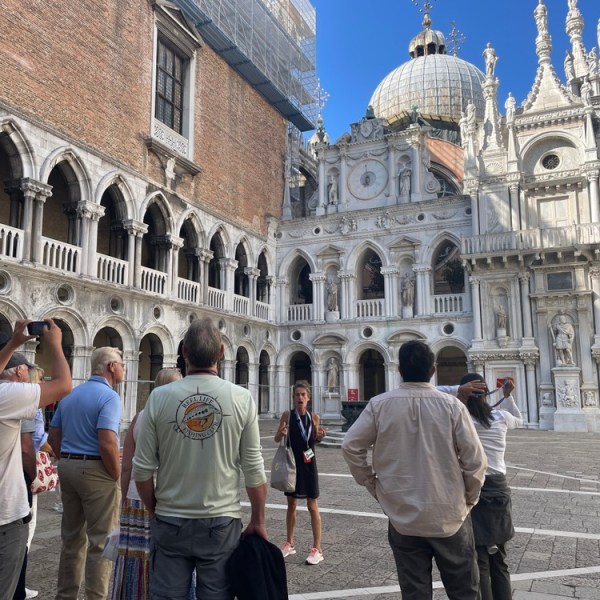 Tour group in a historic courtyard with ornate architecture and sculptures.