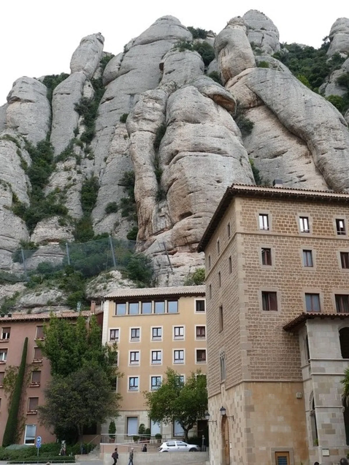 Buildings with arched windows against a backdrop of large, rocky cliffs.