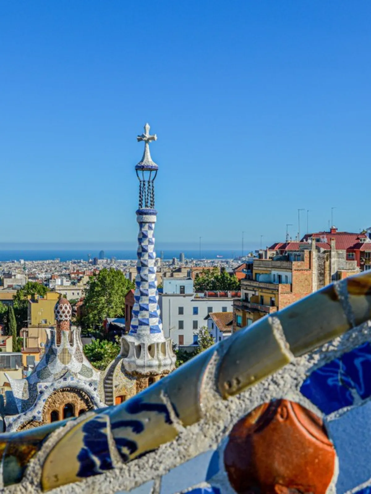 Colorful mosaic and cityscape view with sea, from Park Güell, Barcelona.