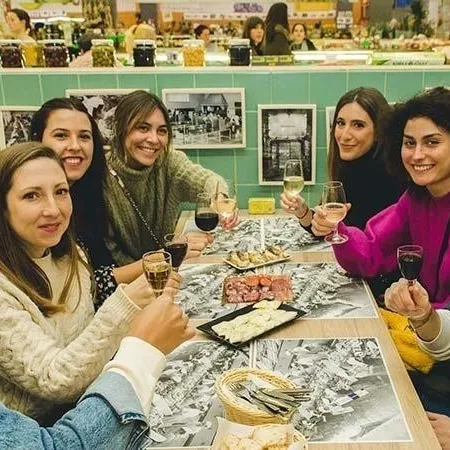 Group of seven people sitting at a table with food and drinks, smiling at the camera.