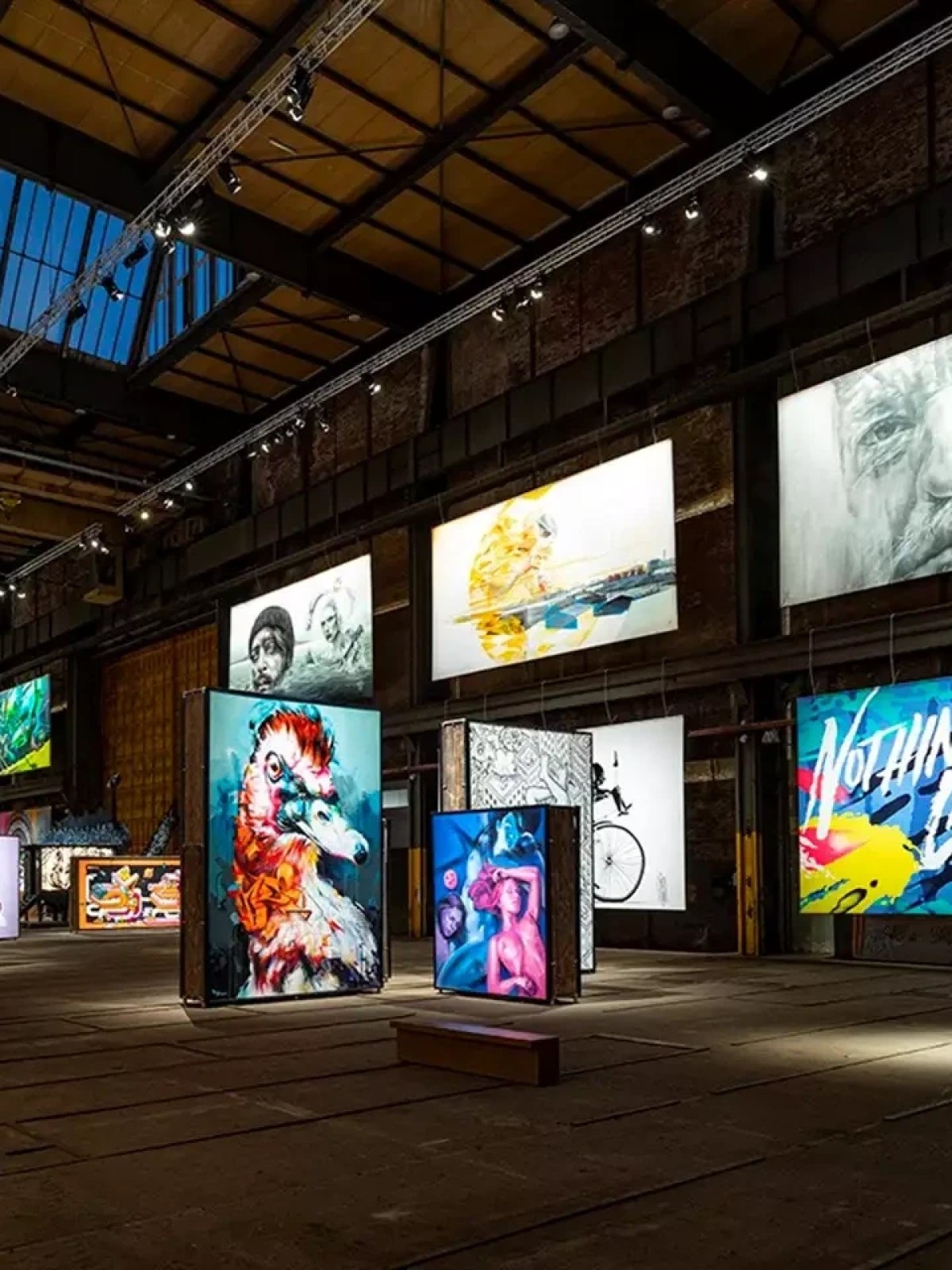 Gallery with brightly lit eclectic artworks on display in an industrial space.