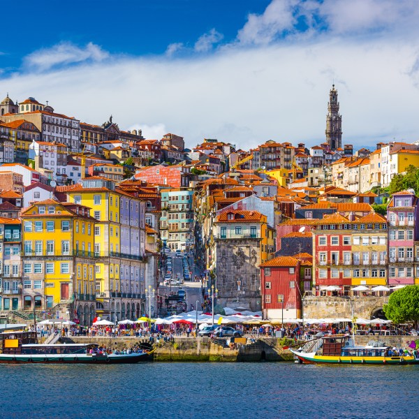 Colorful hillside buildings in Porto, Portugal with boats on the Douro River.