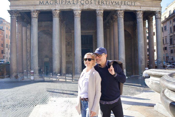 Two people stand in front of the Pantheon in Rome on a sunny day.